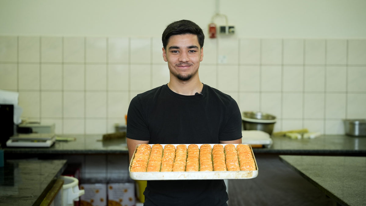 Back-Lava Mitarbeiter präsentiert ein frisches Blech Baklava in der Backstube